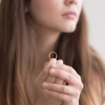 Woman holding wedding ring while considering divorce.