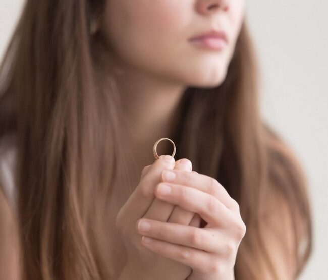 Woman holding wedding ring while considering divorce.