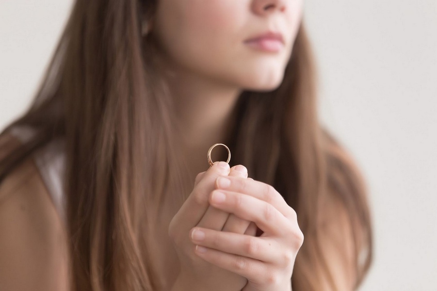 Woman holding wedding ring while considering divorce.