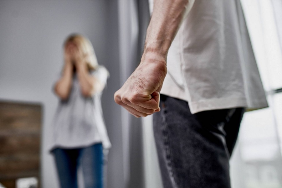 Man with clenched fist in foreground and distressed woman in background representing domestic violence and custody issues.