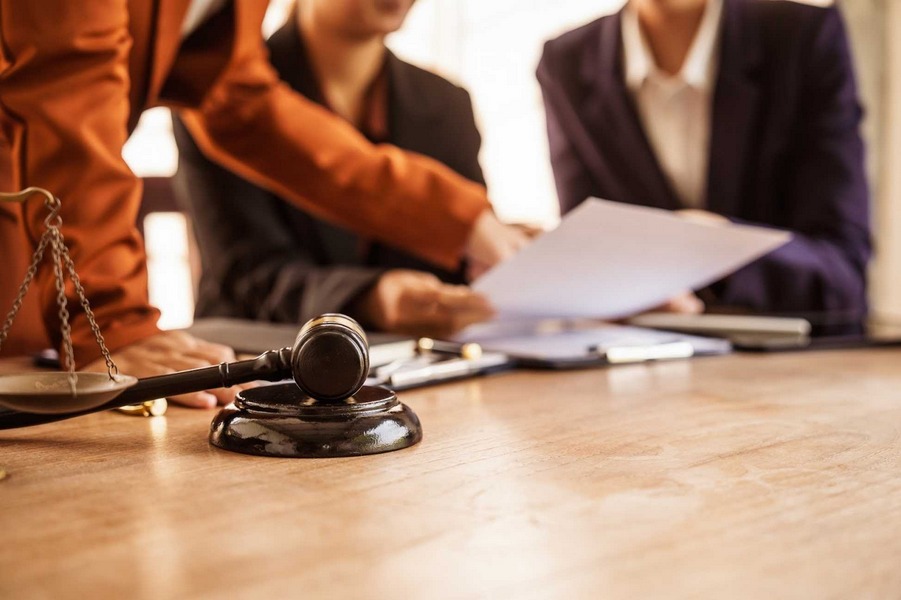 Lawyers reviewing divorce documents at a table with gavel and scales of justice.